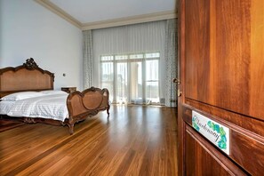 Una camera spaziosa con un letto grande, un armadio in legno e vista attraverso una finestra con tende leggere.