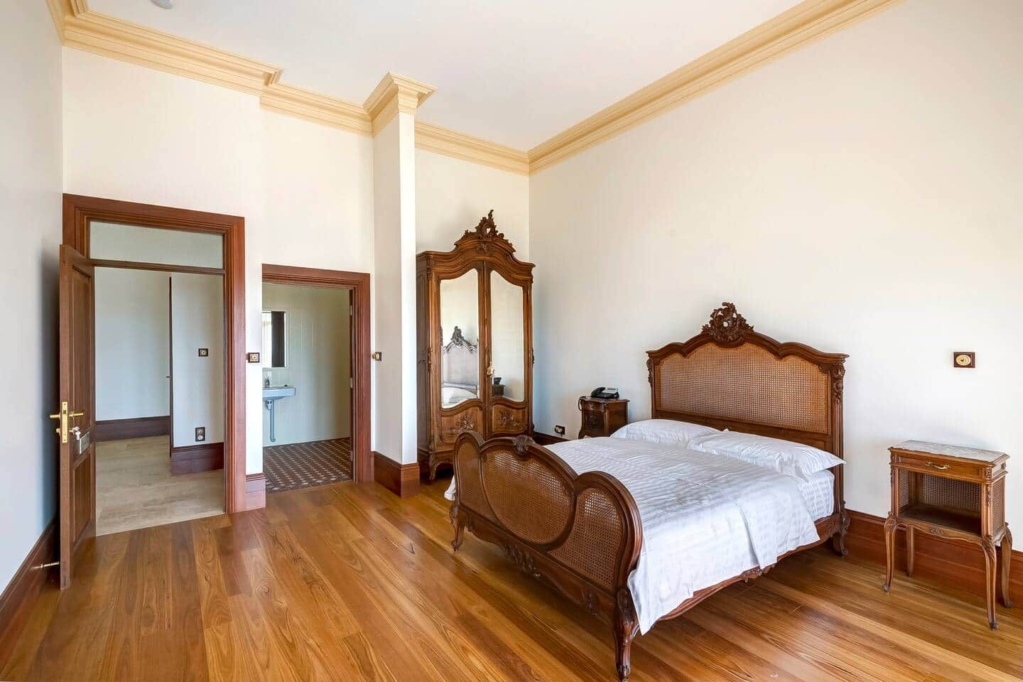 Une chambre à coucher avec un lit en bois, une commode en bois, un miroir et une table de chevet.