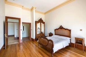 A bedroom with a wooden bed, a wooden dresser, a mirror, and a nightstand.