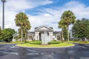 A building with a central fountain, surrounded by palm trees and a well-maintained lawn. - 15 Min to Disney | Kissimmee 3BR/2BA | Sleeps 10 (Kissimmee)