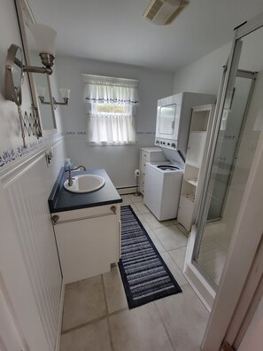 Un baño pequeño con lavamanos, espejo y lavadora incorporada.