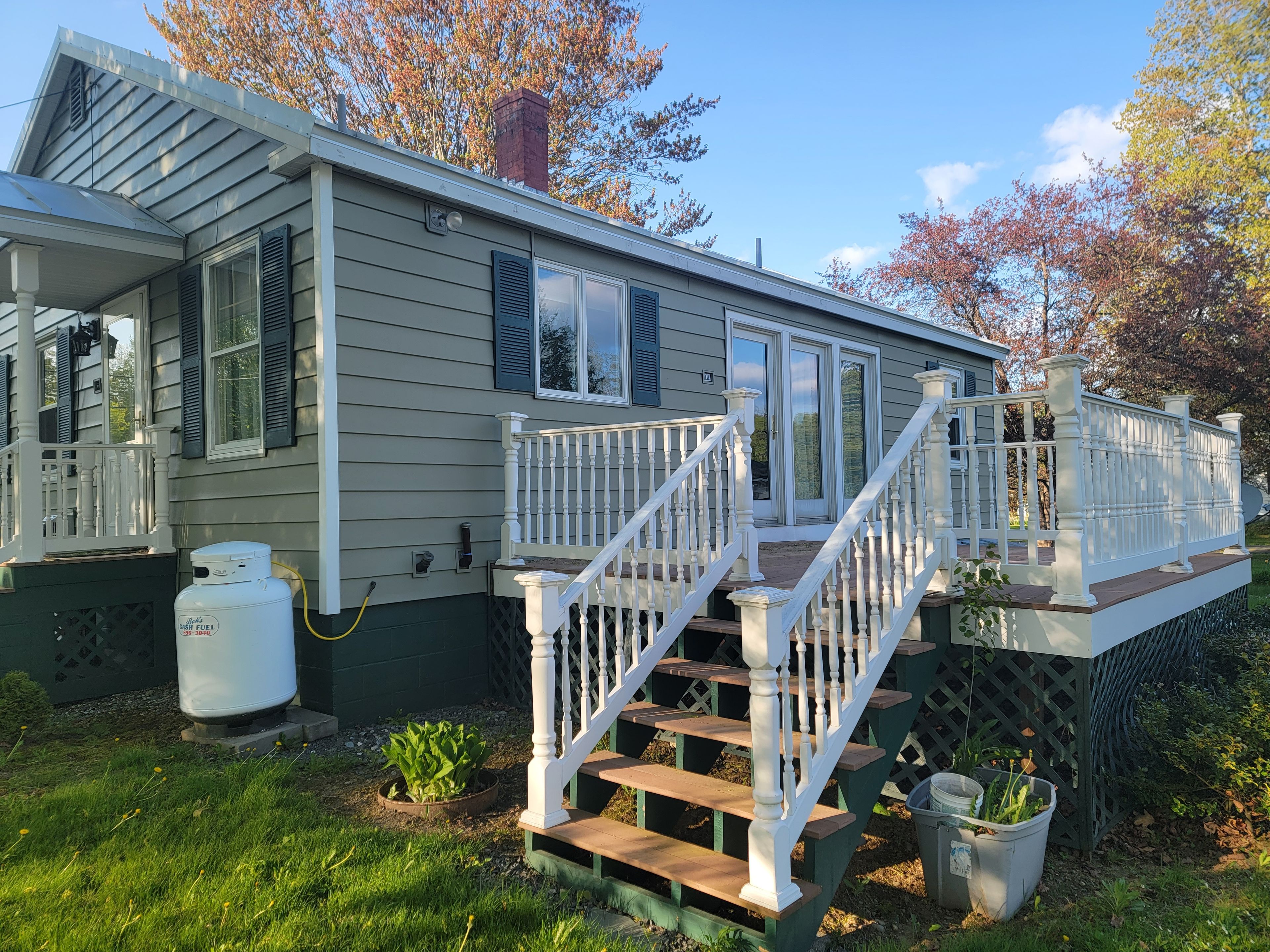 A house with a front porch, a staircase, and a gas tank.