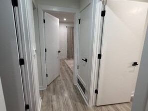 A hallway with white doors, a visible vent, and a rug on the floor. - Modern 3BR near UT Stadium, Domain & Downtown Austin (Austin)