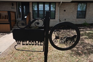 A welcome sign with a horse-drawn carriage design in front of a building with a stone facade and a number '2101' on the door. - Modern 3BR near UT Stadium, Domain & Downtown Austin (Austin)