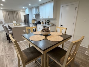 A modern kitchen with white cabinets, a central island, and a dining table with four chairs. - Modern 3BR near UT Stadium, Domain & Downtown Austin (Austin)