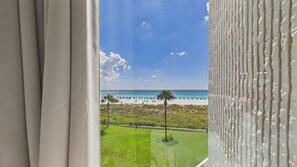 A view of a beach with a clear sky, palm trees, and umbrellas. - Gulfside Getaway 319-3rd Floor Beachfront-Sleeps 4 (Panama City)