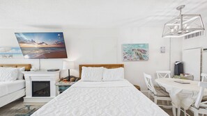 Ein Hotelzimmer mit Bett, Schreibtisch, Sessel, Fernseher und Bildern an den Wänden.