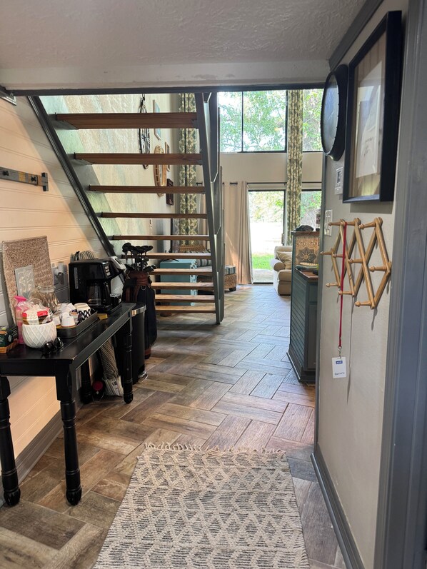 A kitchen with a herringbone floor, wooden cabinets, and a herringbone staircase leading to an outdoor area.
