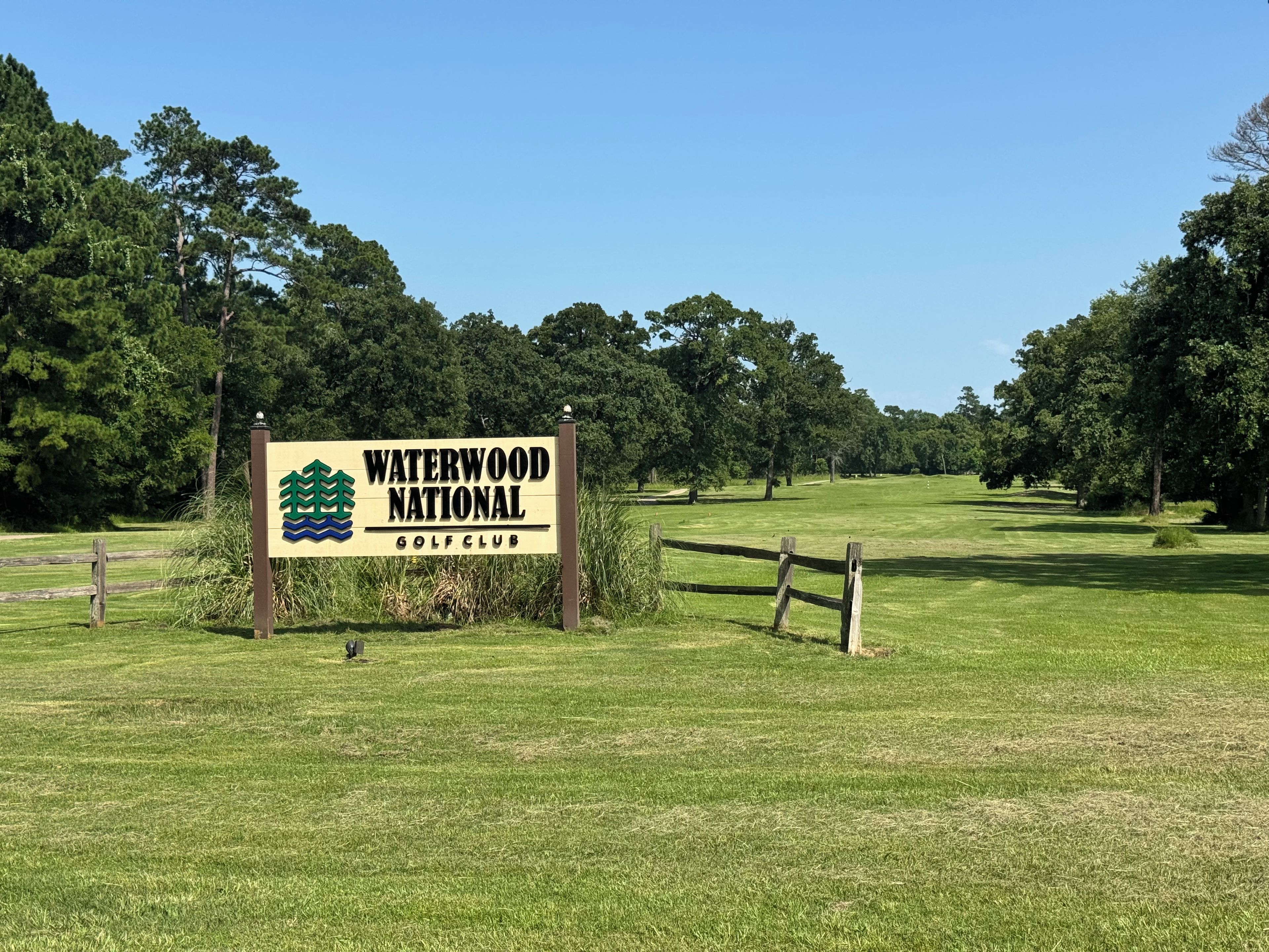 A golf course sign with a logo and the name 'Waterwood National Golf Club' in a grassy area with trees in the background.