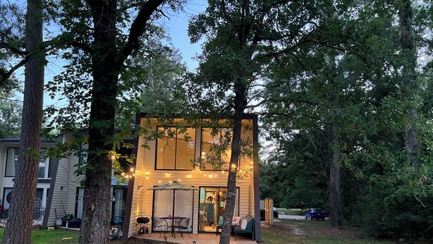 Una casa moderna con un patio, rodeada de árboles.