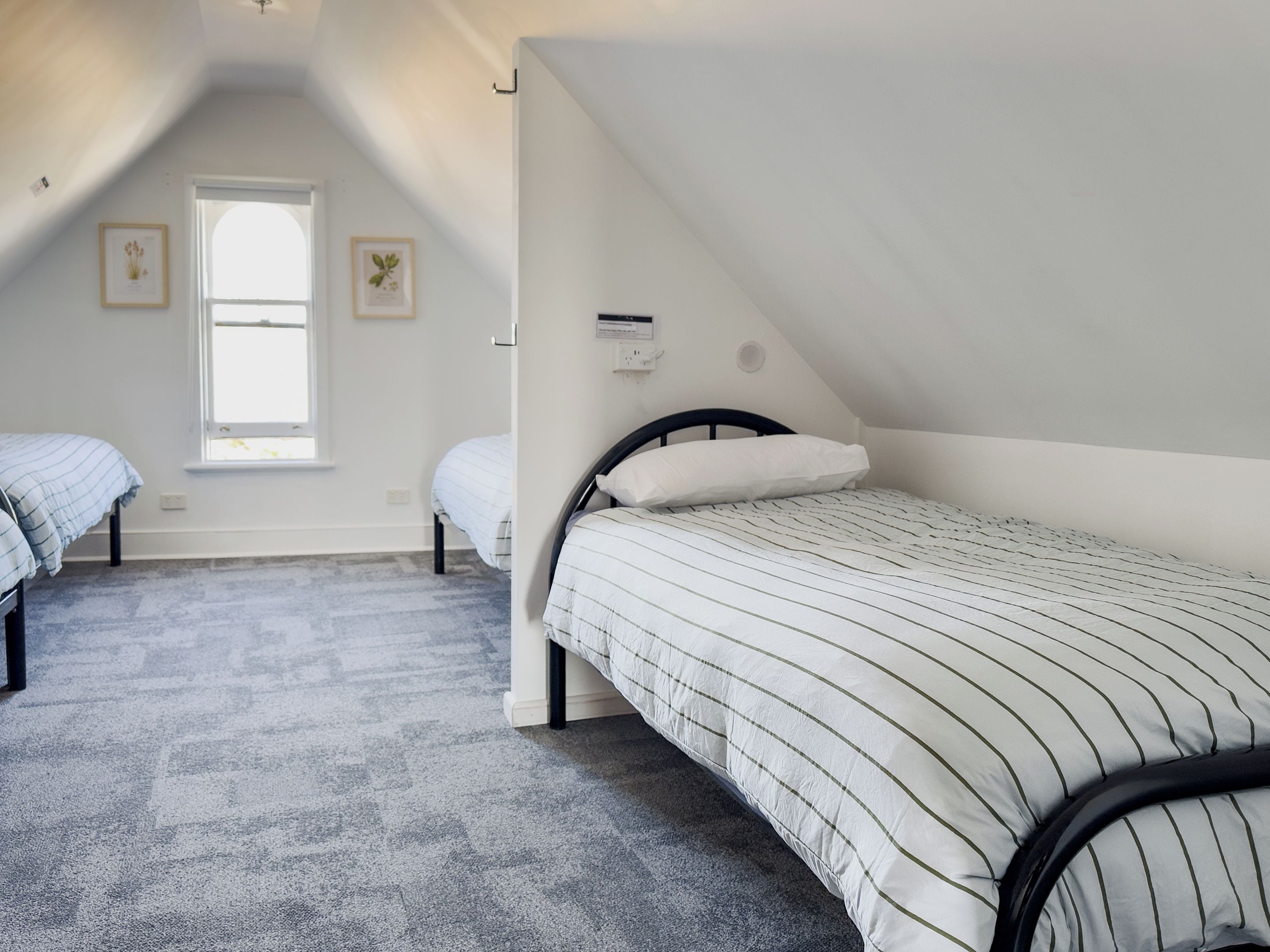 A room with two single beds, a window, and a ceiling fan.