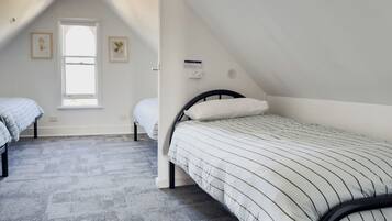 A room with two single beds, a window, and a ceiling fan.