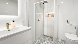 A modern bathroom with a glass-enclosed shower, a white sink, and a toilet. - The Fenway Hostel (Invermay)