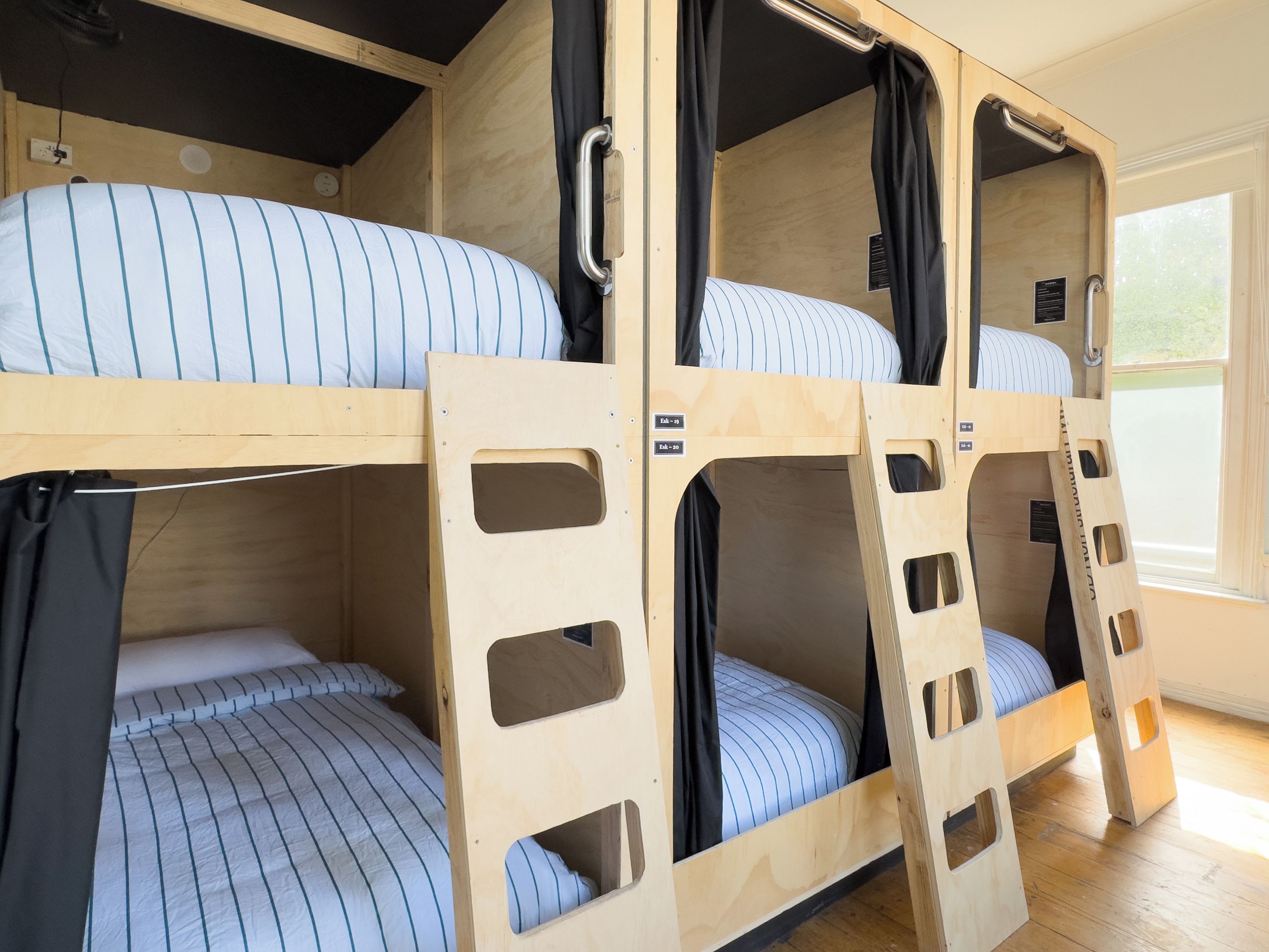 Een slaapkamer met stapelbedden, houten wanden en een raam.