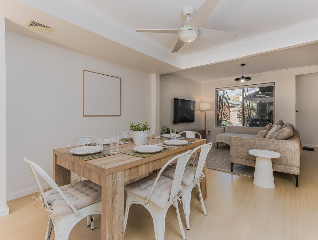 A modern living space with a dining area, a sofa, and a television.