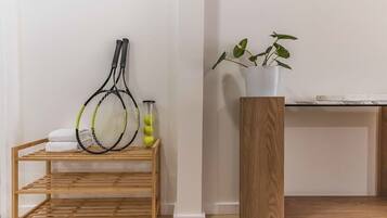 A wooden rack with tennis rackets and a potted plant on a white wall.