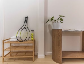 A wooden rack with tennis rackets and a potted plant on a white wall. - Sunkissed at Kirra (Tweed heads)