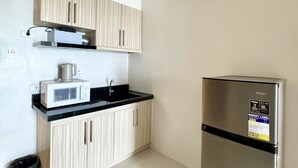 A kitchen with a stainless steel refrigerator, a microwave, and wooden cabinets. - Royal Oceancrest Panglao 1 (Dauis)