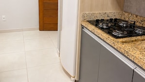 A kitchen with a gas stove, a white refrigerator, and wooden cabinets.