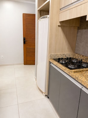 A kitchen with a gas stove, a white refrigerator, and wooden cabinets.