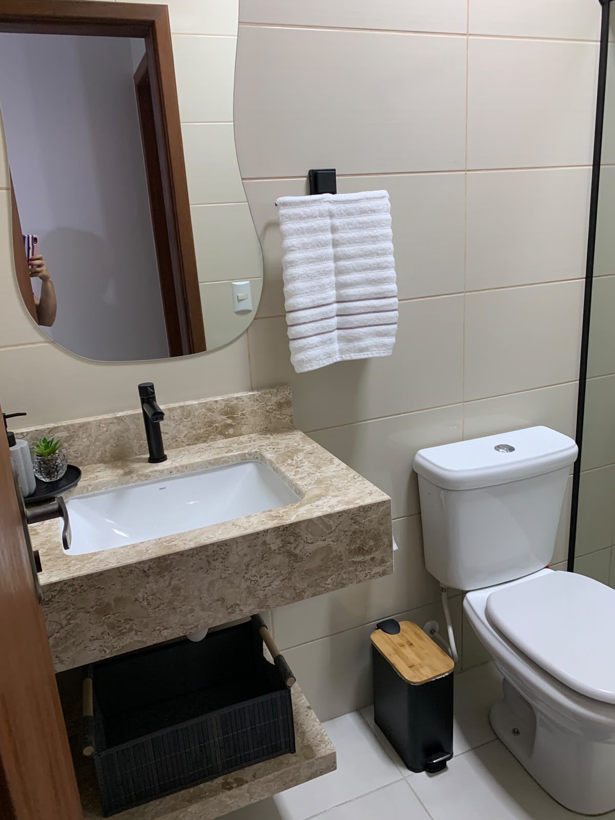Casa de banho com lavatório, sanita e toalha pendurada na parede.