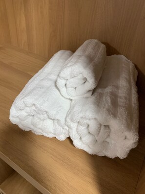 A pair of white towels folded and placed on a wooden shelf.