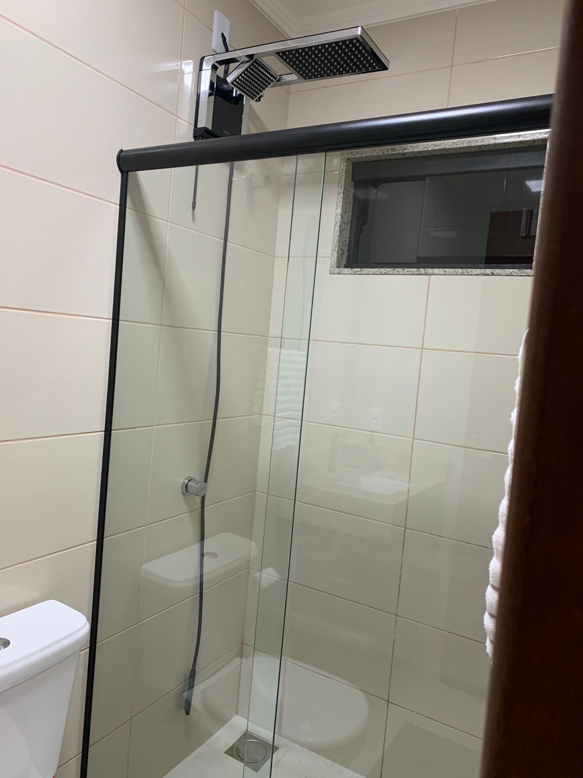 Zona de banyera amb envàs de vidre, vàter visible i plat de dutxa.