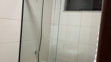 A glass-enclosed shower area with a visible drain and a showerhead.