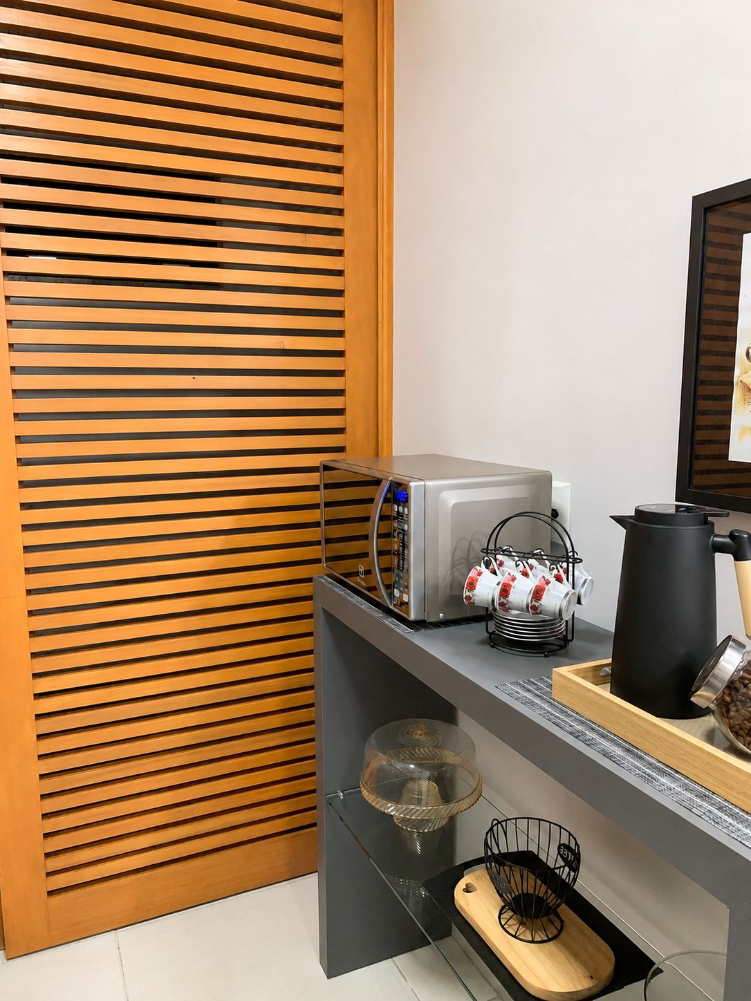 A kitchen with a coffee machine, a kettle, and a coffee pot on the counter.