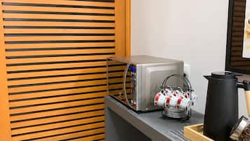 A kitchen with a coffee machine, a kettle, and a coffee pot on the counter.