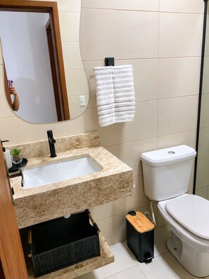 Een badkamer met een wastafel, toilet en spiegel.