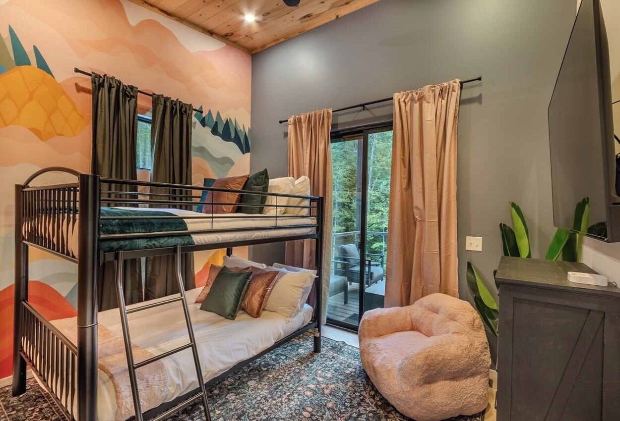 A bunk bed room with a view to the outside, a small seating area, and a cabinet.