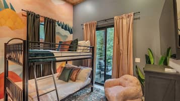 A bunk bed room with a view to the outside, a small seating area, and a cabinet.