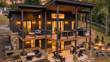 A two-story house with a covered patio, stone exterior, and outdoor seating area.