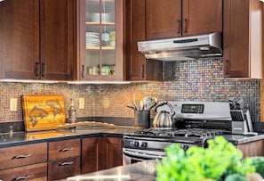 A kitchen with wooden cabinets, a stainless steel range hood, and a tiled backsplash.