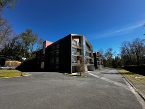 A modern multi-story building with balconies and a parking lot. - Espaço Bosque Pucón: Nature Near the City Center (Pucon)