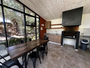A modern kitchen with a large window, a dining table, and a built-in oven. - Espaço Bosque Pucón: Nature Near the City Center (Pucon)