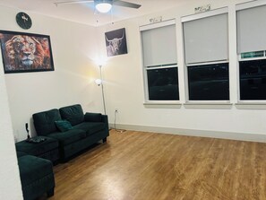 A living room with a green sofa, a standing lamp, and two framed pictures on the wall. - Serene 1-bedroom apartment with luxurious living-Downtown Dallas (Dallas)