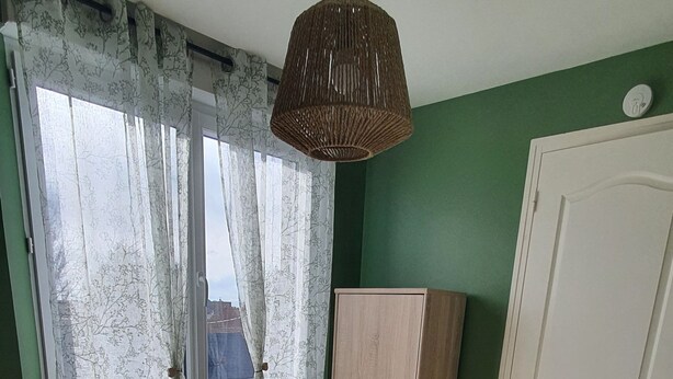 Ein Schlafzimmer mit einem Bett, einem Kleiderschrank, einer Tür und einem Fenster mit Vorhängen.