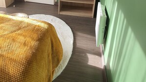 Ein Zimmer mit einem Bett, einem Fernseher auf einem Schrank, einer Tür und einem Heizkörper.
