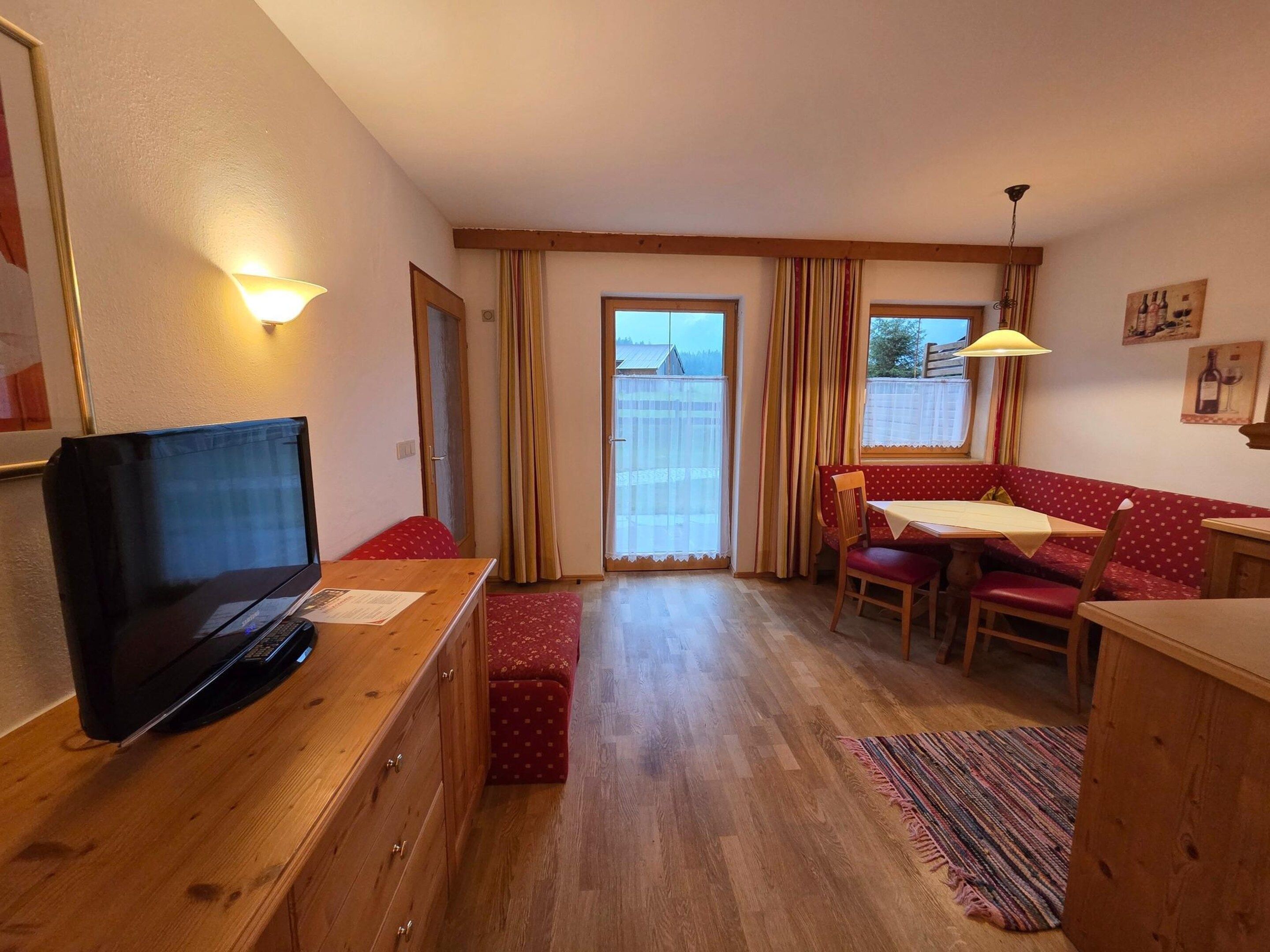 A cozy room with a television, a dining table, and a bench.