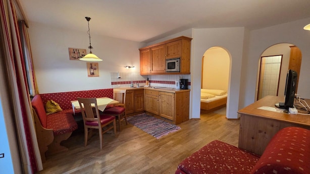 A compact living space with a kitchenette, a dining area, and a bedroom. - Cozy Holiday Apartment (Achenkirch)