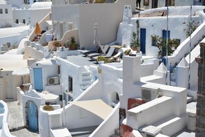 A white-washed building with blue doors and windows, a staircase, and outdoor seating. - Zoe Aegeas Traditional Houses (Santorini)