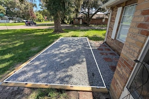 A residential property with a gravel driveway, a wooden deck, and a brick house.