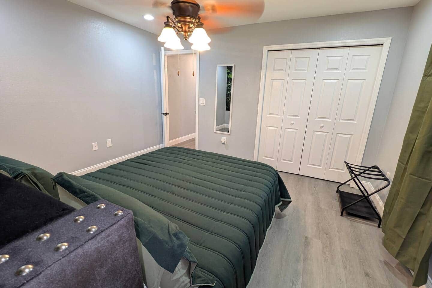 Ein Schlafzimmer mit einem Bett, einem Sessel, einem Kleiderschrank und einem Deckenventilator.