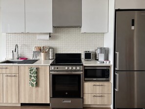 A modern kitchen with stainless steel appliances, a microwave, a toaster, and a coffee maker. - Modern Downtown Toronto Studio with Balcony & Stunning City Views. (Toronto)
