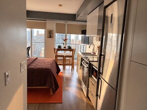 A compact living space with a kitchenette, a dining area, and a bed. - Modern Downtown Toronto Studio with Balcony & Stunning City Views. (Toronto)