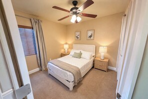 A bedroom with a bed, two bedside tables with lamps, a ceiling fan, and a window with curtains. - Colorado Springs Family Retreat 4BR, Game Loft & Garage (Colorado Springs)