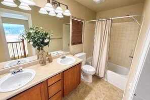 A bathroom with two sinks, a toilet, a bathtub, and a shower curtain. - Colorado Springs Family Retreat 4BR, Game Loft & Garage (Colorado Springs)
