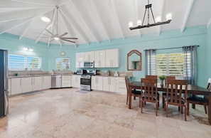 A spacious kitchen with white cabinets, a dining table with chairs, and a ceiling fan. - Luxury 1 bedroom Waterfront Villa with Private Pool and Spacious Deck (Frederiksted)